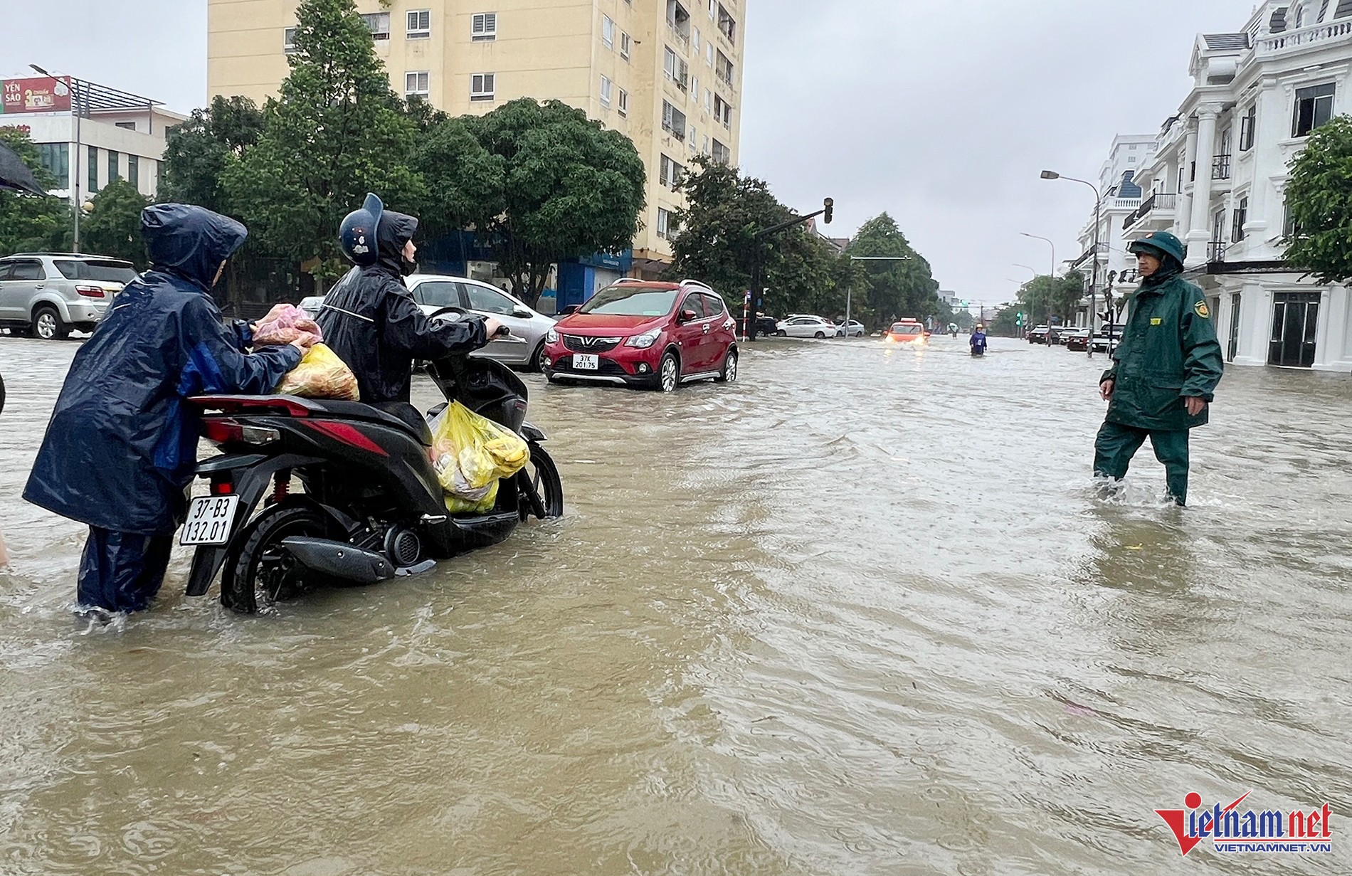 Lực lượng chức năng hỗ trợ người dân di chuyển xe máy qua vùng ngập sâu