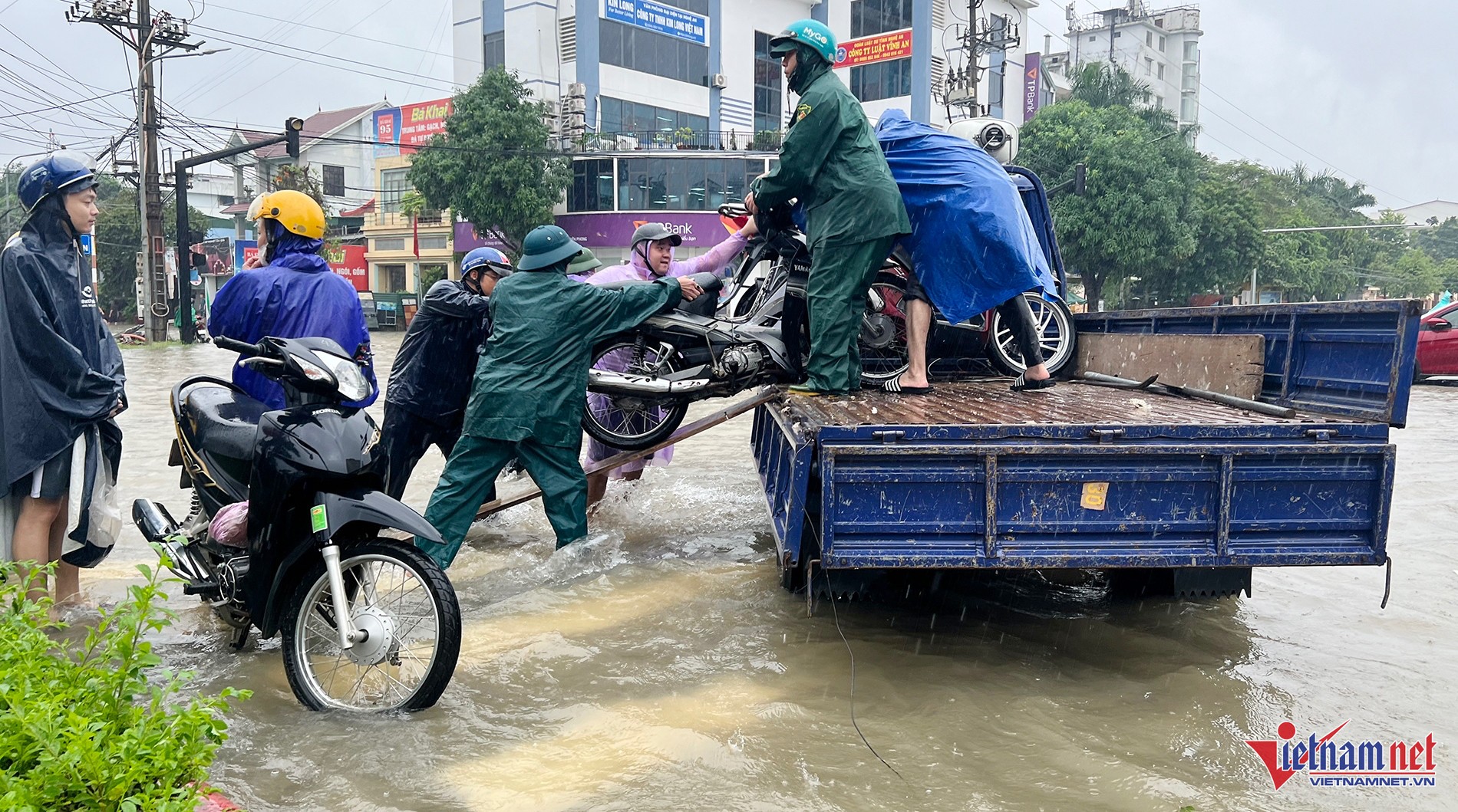 Lực lượng chức năng dùng ô tô hỗ trợ di chuyển xe máy khỏi vùng ngập ở TP Vinh